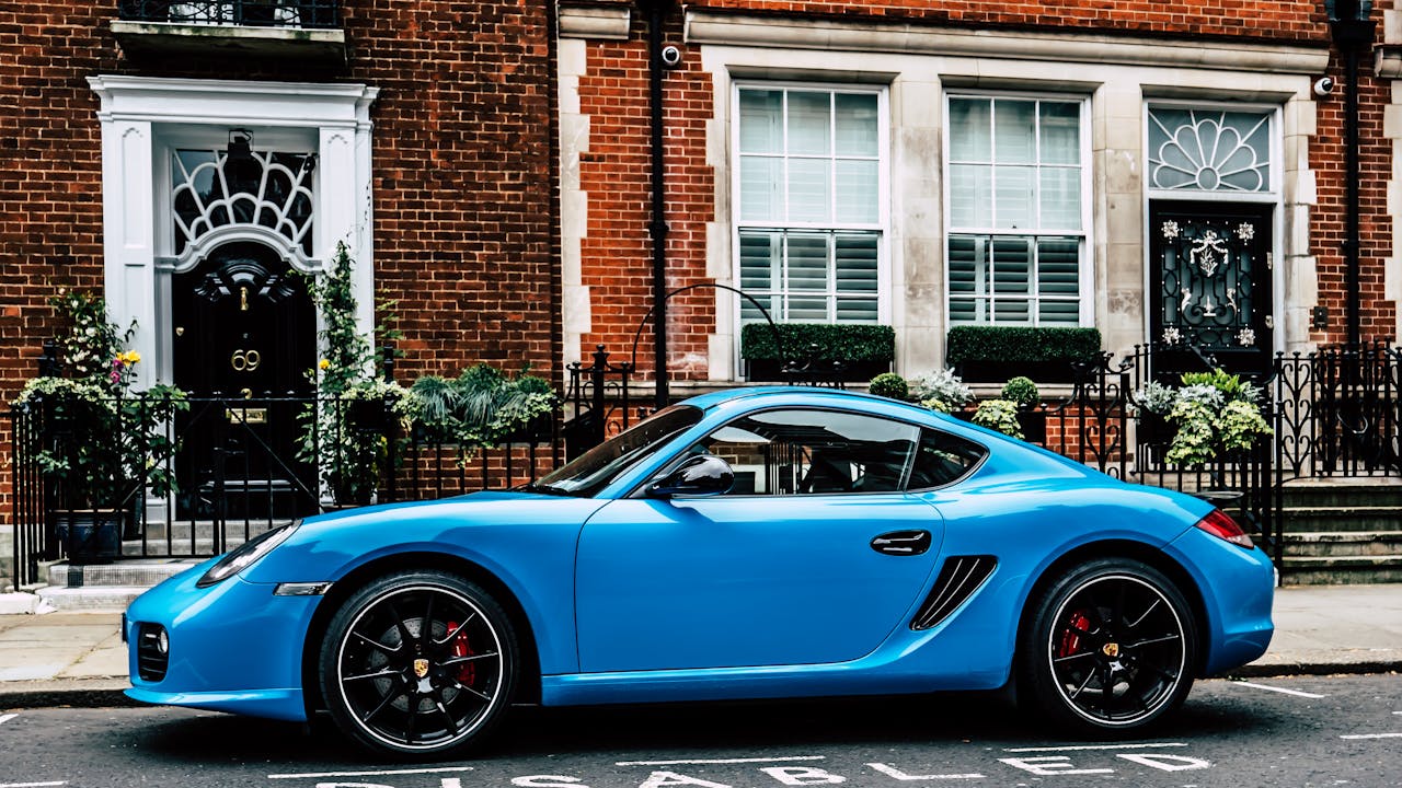 A sleek blue sports car parked in front of classic brick buildings in London.